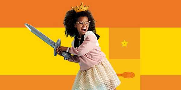 A girl wearing a crown pretending to be a princess against a yellow background.